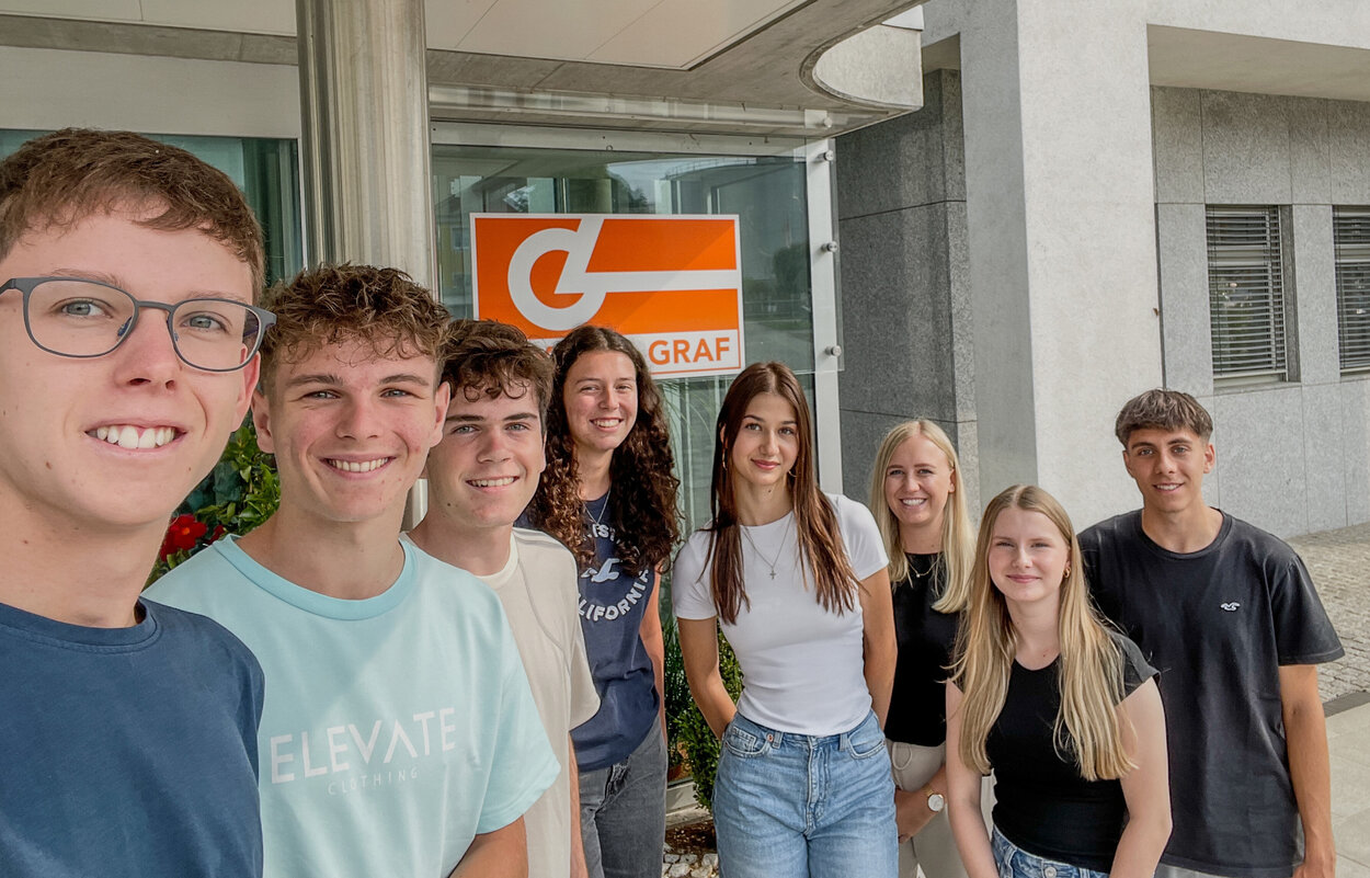 Gruppe von Praktikanten macht Selfie vor Leyrer + Graf Firmengebäude